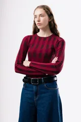 Top de tejido de punto ajustado al cuerpo, con diseño de rayas verticales en tonos bordó y rojo. Presenta cuello redondo y mangas largas.