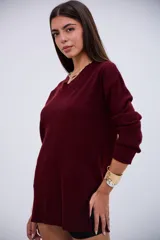 Sweater de punto acanalado en color bordó, con cuello en V y mangas largas. Presenta un diseño de corte recto con aberturas laterales en el ruedo.