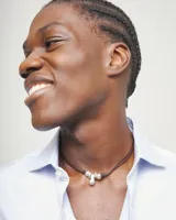 Collar de cuero marrón con doble tira, adornado con tres bolas de aleación de metales bañadas en plata de ley y un colgante central en forma de gota. Cuenta con cierre de mosquetón y cadena de extensión plateada.