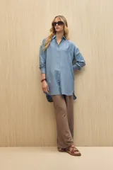 Vestido camisero negro de silueta amplia, con cuello camisero, botonadura frontal completa y mangas largas.