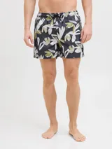 Short de baño con estampado floral abstracto en tonos verdes, beige y blancos sobre base gris oscuro. Presenta cintura elástica con cordón ajustable y bolsillos laterales.