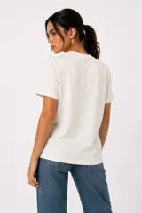 Remera de algodón color blanco off-white, de manga corta, cuello redondo a la base y corte holgado. Presenta un estampado frontal con diseño de corazón en tonos marrones y azules, con detalles de strass y texto.