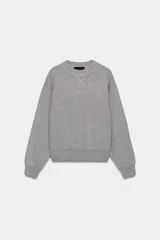 Jersey gris de cuello redondo y manga larga, con detalle de costura en V en el escote y ribetes acanalados.