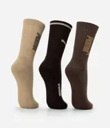 Kit de tres pares de medias deportivas Puma de caña larga. Un par es beige con dos rayas marrones y logo de Puma. Otro par es blanco liso. El tercer par es marrón oscuro con dos rayas blancas y logo de Puma. Todas están confeccionadas en algodón.