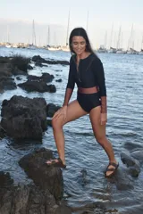 Traje de baño enterizo de manga larga en color negro con detalles en color cobre en la cintura y los puños. Presenta un cierre frontal y diseño de corte clásico.