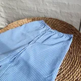 Pantalón celeste con rayas verticales blancas, de corte recto y cintura elastizada con cordón ajustable.