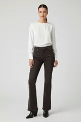 Jeans de corte flare color marrón oscuro, confeccionados en denim, con tiro medio, bolsillos clásicos y detalle de dobladillo deshilachado con pequeña abertura lateral en los tobillos.