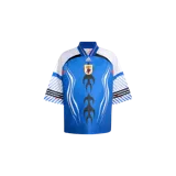 Camiseta de fútbol Adidas modelo Bringback Remixed Japan Jersey, color azul con detalles en blanco, negro y rojo. Presenta un diseño retro con cuello en V, mangas cortas y un llamativo estampado frontal de llamas y líneas onduladas.