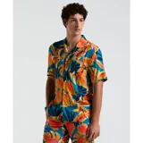 Camisa de hombre de manga corta con estampado de hojas tropicales en tonos naranja, azul y verde. Tiene cuello clásico, cierre con botones y un bolsillo en el pecho.