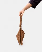Bolso de mano tipo sobre confeccionado en gamuza color marrón, con diseño de bordes trenzados y detalle de flecos largos laterales. Incluye herrajes metálicos plateados y correa desmontable.