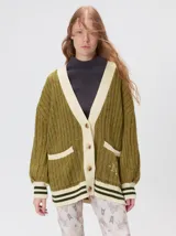 Cardigan de tejido de punto con diseño de ochos, corte oversize y mangas largas con puños acanalados. Presenta un escote en V con solapas en contraste, cierre frontal con botones y dos bolsillos delanteros con bordes en contraste. El diseño incluye detalles de rayas en los puños y en el ruedo.