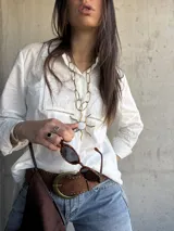 Camisa blanca de manga larga con detalles de broderie y calados en el frente y las mangas.