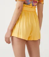 Short femenino modelo clochard, confeccionado en una mezcla de viscosa, lino y algodón. Presenta un diseño de tiro alto con cintura elástica y lazo ajustable del mismo tejido, ofreciendo un calce cómodo y versátil.