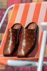 Zueco marrón de cuero con tachas plateadas.