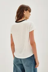 Remera de algodón color blanco con cuello redondo en contraste negro. Presenta un estampado frontal con la frase 'Self Love Club' y un diseño de labios en color negro.