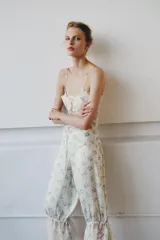 Pantalón bombacho de tiro medio y cintura elástica, confeccionado en viscosa con estampado floral y rayas sutiles. Presenta bajo ajustable con lazada y aplicación de encaje contrastante en el ruedo.