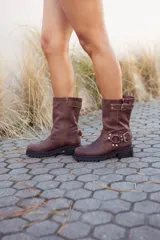 Botas de media caña de cuero color marrón con hebillas metálicas y cierre lateral.