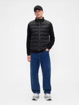 Chaleco puffer acolchado de color beige, con cierre frontal de cremallera, cuello alto y logo de la marca bordado en el pecho.