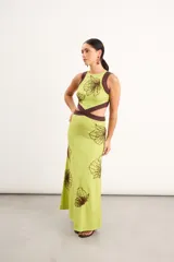 Vestido midi marrón con detalles en rojo, cuello redondo, diseño sin mangas, aberturas cut-out en la cintura y bordados artesanales de flores en contraste.
