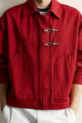 Cazadora relaxed fit de Zara confeccionada en tejido de algodón rojo con efecto lavado. Presenta cuello solapa, manga larga, bolsillos de plastrón en la cadera y cierre frontal de cremallera oculta con solapa y alamares metálicos.