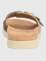 Sandalia tipo slide con tira ancha de tejido texturizado en tono beige y detalle de hebilla circular decorativa en color marrón. Cuenta con plantilla anatómica y suela de poliuretano dentada en color crema.