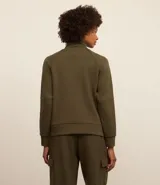 Buzo deportivo verde oliva de microfibra pesada, con cuello alto con cremallera, recorte en los hombros y dos aberturas en la parte de abajo.