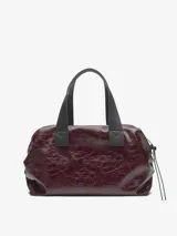 Bolso tipo bowling de Adolfo Dominguez, color borgoña oscuro con acabado brillante y textura craquelada. Posee asas de mano negras y un cordón ajustable lateral.