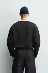 Camiseta de manga larga con corte relajado y cuello redondo. Presenta un diseño de doble capa con acabados en rib a contraste en el cuello y el ruedo.