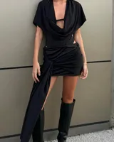 Minifalda negra con drapeado lateral y abertura en la pierna izquierda.