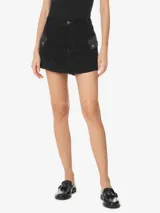 Minifalda negra de sarga de algodón, con cintura alta, pretina con trabillas, dos bolsillos cargo laterales con solapas abotonadas, aberturas delanteras y traseras, cierre frontal con cremallera y botón, y etiqueta de la marca en la espalda.