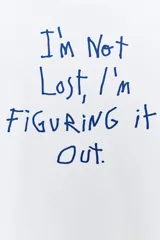 Camiseta de algodón de corte regular, con cuello redondo y manga corta. Presenta un estampado frontal con texto en color azul oscuro sobre fondo blanco.