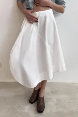 Falda midi de tiro medio en color blanco, con diseño asimétrico en el bajo y bolsillos delanteros. Cuenta con cierre lateral oculto.