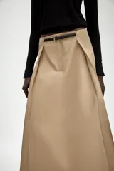Falda midi de tiro alto en color beige, con diseño evasé y pliegues laterales. Incluye un cinturón fino a contraste en color negro con hebilla metálica y cierre frontal con cremallera y gancho.