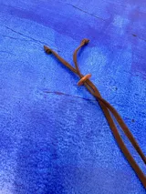 Collar de largo regulable con cordón de cuero y dos piezas colgantes de resina en tonos tierra y marmolados.