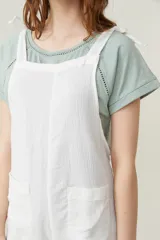 Mono corto color amarillo pastel, con breteles finos que se atan en los hombros, escote recto y dos bolsillos delanteros.