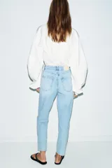 Jeans de tiro alto con corte mom fit, cinco bolsillos y cierre frontal con cremallera y botón.