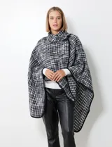 Capa de tejido tweed en blanco y negro, con cuello alto y cierre cruzado con botón de trenca.