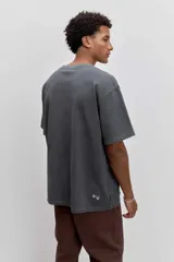 Remera de algodón color verde oscuro, de corte holgado y manga corta, con pequeño estampado gráfico en el pecho.