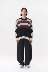 Buzo de tejido de punto con diseño geométrico y combinación de colores en contraste. Presenta cuello redondo, mangas largas y corte oversized.