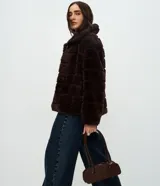 Campera de pelo artificial color marrón oscuro, con diseño de gajos horizontales, manga larga y cuello alto estructurado.