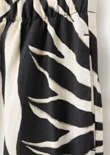 Pantalón fluido de corte recto con estampado tropical y cintura elástica, confeccionado en mezcla de viscosa y poliamida. Cuenta con bolsillos laterales.