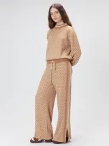 Sweater de punto jacquard con diseño texturizado, cuello alto y puños acanalados en contraste. Presenta un corte holgado y diseño inspirado en patrones naturales.