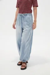Pantalón jean de corte globo con cintura elástica y cordón ajustable, tiro medio y botamangas fruncidas con elástico.