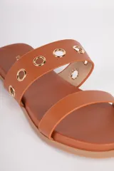 Sandalias bajas color suela, con doble tira en el empeine. La tira superior presenta argollas metálicas doradas.