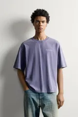 Camiseta relaxed fit de color gris con efecto lavado, cuello redondo y manga corta. Cuenta con un pequeño texto estampado en contraste en el pecho.