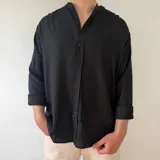 Camisa de lino negra de manga larga, con cuello mao y cierre frontal con botones.