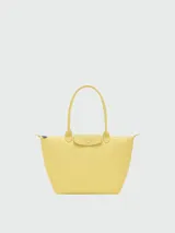 Bolso tote grande modelo Le Pliage de Longchamp, color amarillo, con asas largas de hombro, solapa frontal de cuero con cierre de botón a presión y cierre superior de cremallera.