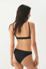 Conjunto de bikini negro con corpiño triangular con tirantes finos y detalle de borde festoneado, y bombacha clásica con detalle de borde festoneado.