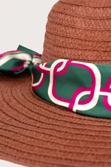 Pañuelo cuadrado con diseño estampado de cadenas y eslabones entrelazados en tonos verde, fucsia y blanco, con borde enmarcado y logo de la marca repetido en el contorno.