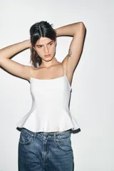 Top negro ajustado al cuerpo con escote recto y tirantes finos. Presenta un bajo con corte peplum.